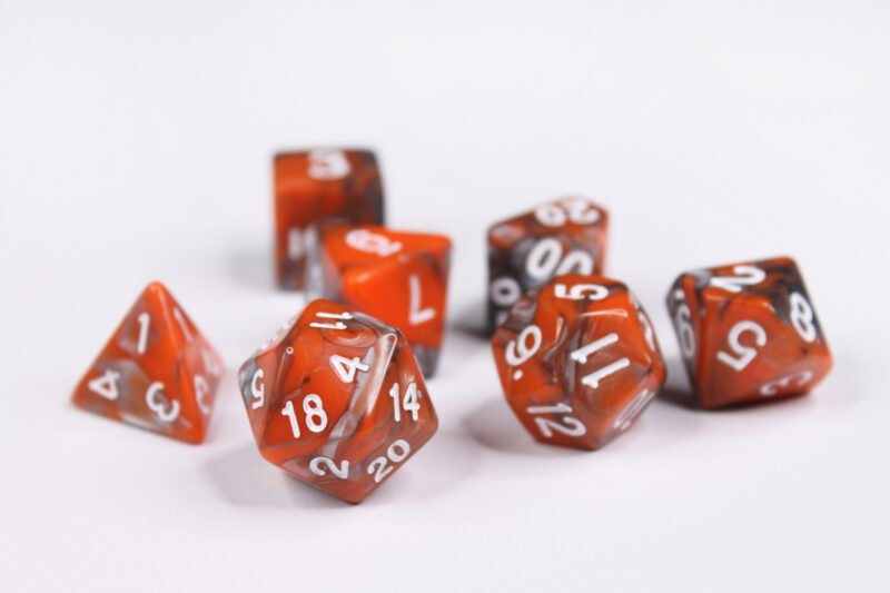 Collection of seven acrylic dice with swirled pearly silver and orange colouring and white numbers