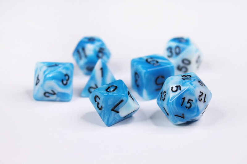Collection of seven acrylic dice with swirled white and turquoise blue colouring and black numbers