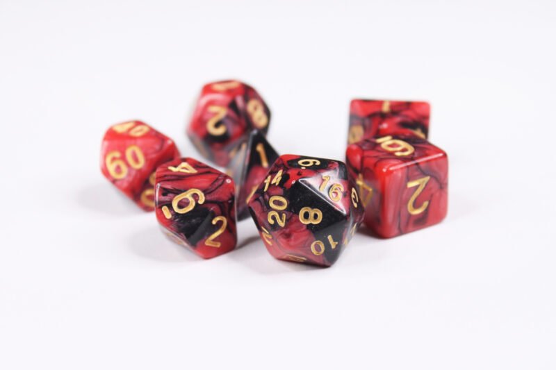 Collection of seven acrylic dice with swirled pearly black and red colouring and gold numbers