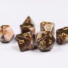 Collection of seven acrylic dice with swirled brown and cream colouring and gold numbers