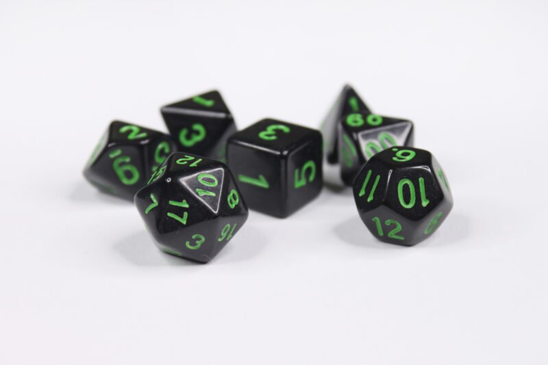 Collection of seven acrylic dice with plain black colouring and green numbers