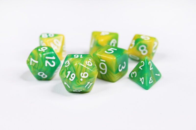 Collection of seven acrylic dice with swirled green and yellow colouring and white numbers