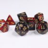 Collection of seven acrylic dice with swirled pearly black and red colouring and gold numbers