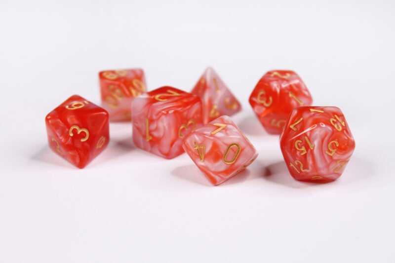 Collection of seven acrylic dice with swirled pearly red and white colouring and gold numbers