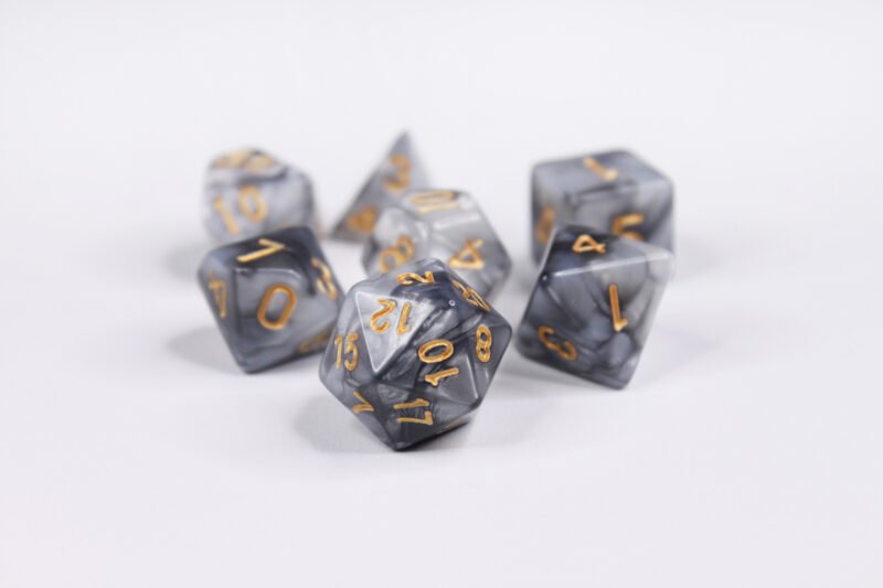 Collection of seven acrylic dice with swirled pearly grey and silver colouring and gold numbers