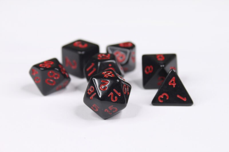Collection of seven acrylic dice with plain black colouring and red numbers