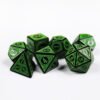 Collection of seven black dice with embossed swirling patterns and green coloured motif and numbering