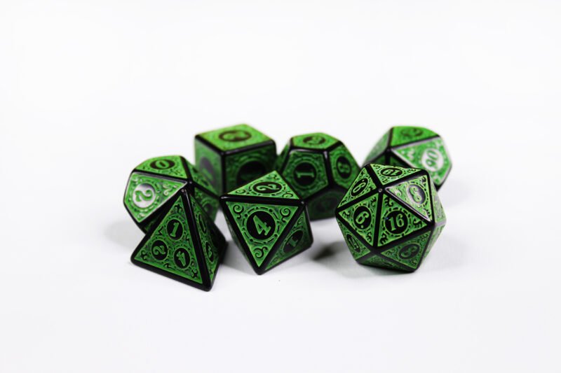 Collection of seven black dice with embossed swirling patterns and green coloured motif and numbering