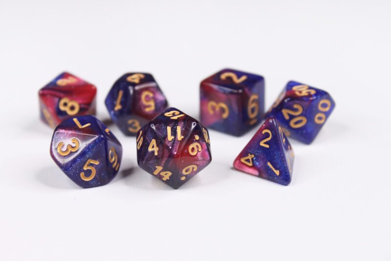 Collection of seven acrylic dice with swirled fine glittery pink and blue colouring and gold numbers