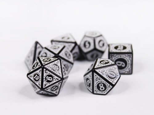 Collection of seven black dice with embossed swirling patterns and white coloured motif and numbering