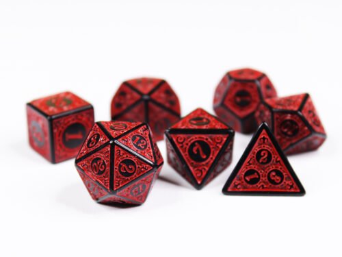 Collection of seven black dice with embossed swirling patterns and red coloured motif and numbering