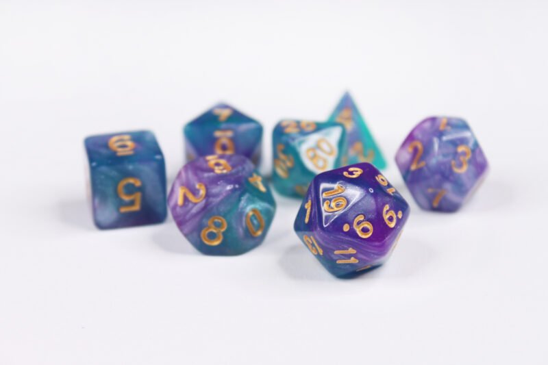 Collection of seven acrylic dice with swirled fine glittery purple and turquoise colouring and gold numbers