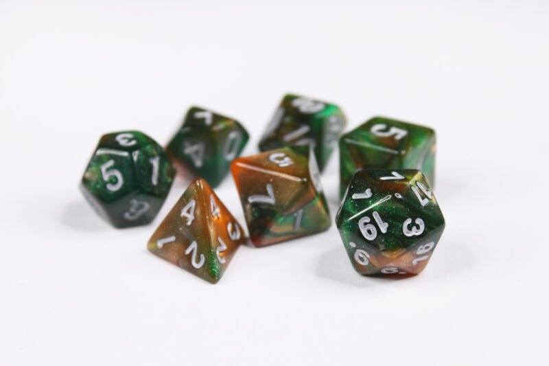Collection of seven acrylic dice with swirled fine glittery green and orange colouring and silver numbers