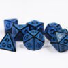 Collection of seven black dice with embossed swirling patterns and blue coloured motif and numbering