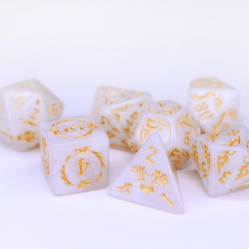 Collection of seven white dice with embossed dragon patterns and gold coloured motif and numbering