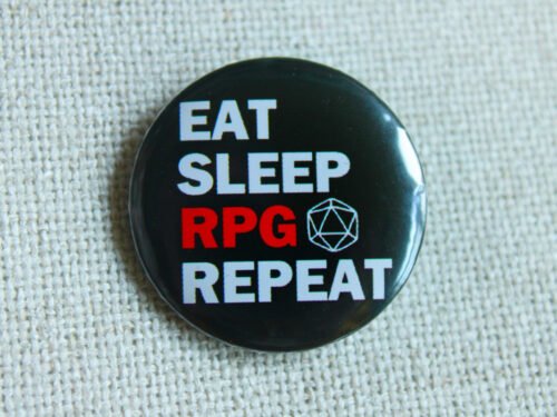 A black button badge showing the text Eat Sleep RPG Repeat and a D20 outline. The word RPG is in red, the rest is in white.