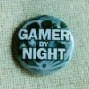 A button badge showing a full moon and the text Gamer By Night across it in white.