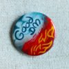 An illustrated button badge with one half that shows blue sky and clouds and text that reads Good DM and another half that shows flames and the text Evil DM.