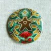 A button badge of a gingerbread meeple with faerie wings a star and fly agaric toadstools