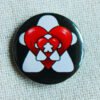 A black button badge whowing repeated images of white meeples and red hearts alternatively getting smaller.