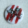 A white button badge with three red stripes, two illustrated hand axes crossed in an x, and the hand drawn text RAGE in red.