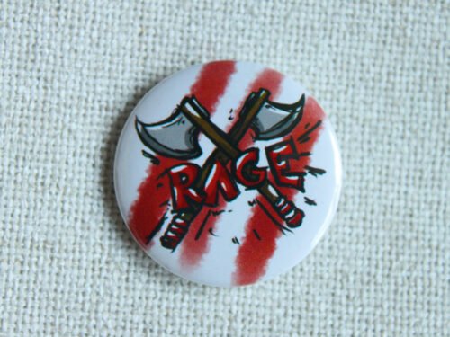 A white button badge with three red stripes, two illustrated hand axes crossed in an x, and the hand drawn text RAGE in red.