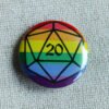 A button badge with a rainbow striped background and the outline of a D20 die in black.