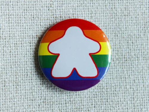 A button badge with a rainbow striped background and the white silhouette of a meeple with a red outline.