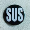 A black button badge showing the large white all caps word SUS as an abbreviation of Suspisious