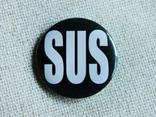 A black button badge showing the large white all caps word SUS as an abbreviation of Suspisious