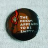 An illustrated button badge showing a fire torch and a dark empty room with the text The Room Appears to be Empty