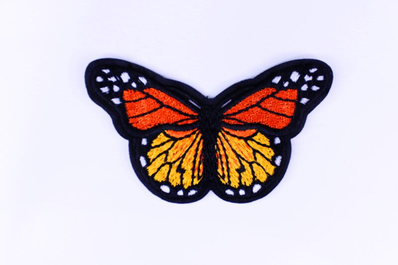 An embroidered patch of a orange black and white monarch butterfly with its wings spread wide.