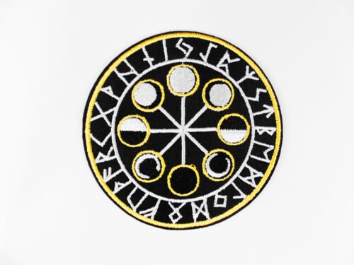A circular embroidered patch of a the eight moon cycles encircled by Norse runes in black white and ochre.