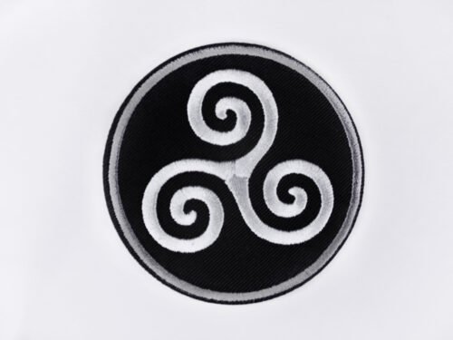 An embroidered patch of a Celtic triskele in the colours black white and grey