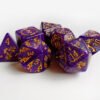 Collection of seven purple dice with embossed dragon patterns and gold coloured motif and numbering.