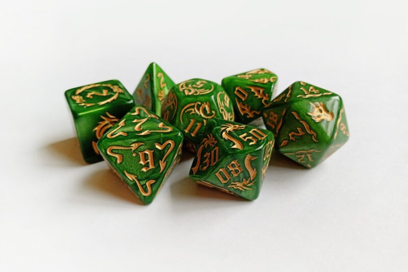 Collection of seven green dice with embossed dragon patterns and gold coloured motif and numbering.