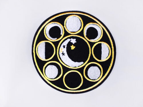 An embroidered patch of a crescent moon with stars encircled by eight different moon phases.